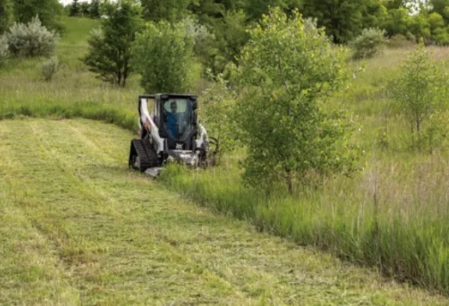 Skid steer brush hogging an overgrown field