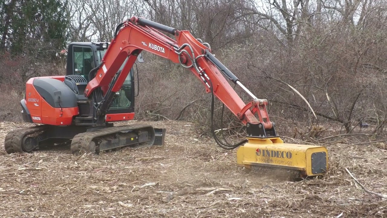 Excavator with a mulching head clearing a site